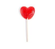 Red candy in the form of a heart on a stick for lovers. White background, isolate, close-up photo