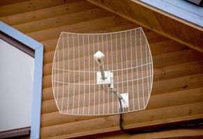 Parabolic antenna for amplifying the signal of cellular communication and the Internet installed in a country house. Strengthening the 4G and 5G Internet signal in the country, close-up photo