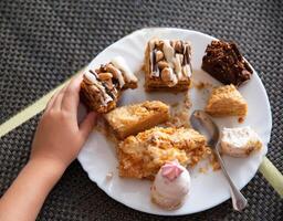 Child's hand holds a cake in a plate, scraps of sweets. Sweet tooth, close-up photo