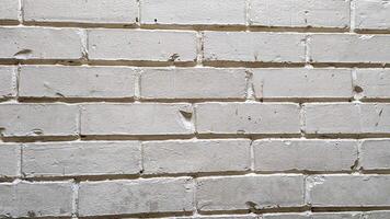 A weathered white brick wall displaying subtle textures and uneven surfaces, likely found in an urban setting, creating a rustic backdrop suitable for various design projects photo