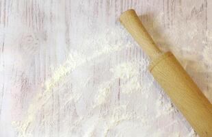 Background for baking with space for text. Rolling pin and flour on a white wooden surface. Top view with empty area for text. photo