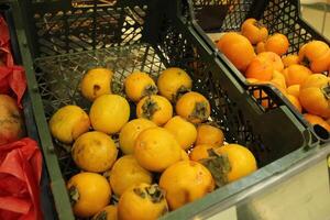Yellow persimmons are in a plastic box in the store. Seasonal fruits and vegetables photo