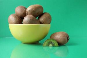 still life kiwi fruit in a yellow bowl plate and next to a kiwi copyspace slice photo