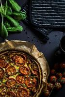 a pizza with tomatoes and spinach on a black background photo