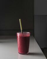 a smoothie with a straw sitting on a counter photo