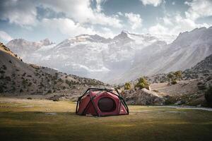 a tent is set up in a field with mountains in the background photo