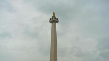 The iconic Monas in Jakarta stands tall against a backdrop of beautiful clouds and lush green grass photo