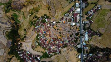 An aerial view of Sade Village in Lombok reveals lush farmland and densely populated homes under the bright midday sun, showcasing vibrant community life. photo