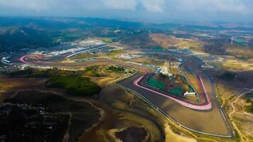 Experience stunning aerial views of hills behind the Mandalika circuit in Lombok, with a breathtaking sunset atmosphere as the camera glides through the clouds. photo