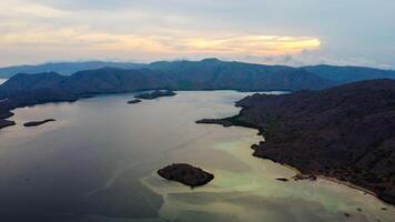 Aerial view of Labuan Bajo harbor at sunset, showcasing numerous pinisi boats docked, with charming local residences surrounding the vibrant scene. photo