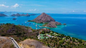 Aerial view of Labuan Bajo harbor at sunset, showcasing numerous pinisi boats docked, with charming local residences surrounding the vibrant scene. photo