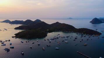 Aerial view of Labuan Bajo harbor at sunset, showcasing numerous pinisi boats docked, with charming local residences surrounding the vibrant scene. photo