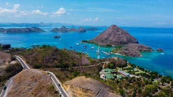 Aerial view of Labuan Bajo harbor at sunset, showcasing numerous pinisi boats docked, with charming local residences surrounding the vibrant scene. photo