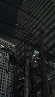 A chaotic bundle of tangled power cables and electrical connections on a utility pole in a densely populated urban area. photo