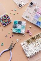 Crafting with colorful beads on a flat workspace with tools and containers in bright daylight photo