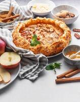 Delicious apple pie with almonds, honey, and cinnamon served on a table with fresh apples and nuts photo