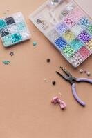 Crafting with colorful beads on a flat workspace with tools and containers in bright daylight photo