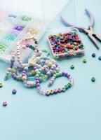 Colorful beads and pliers creating friendship bracelets on blue background photo