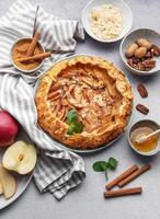 Delicious apple tart with almonds and honey served on a rustic table with fresh apples and spices photo