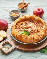 Delicious homemade apple tart displayed on a wooden board surrounded by fresh apples and honey photo