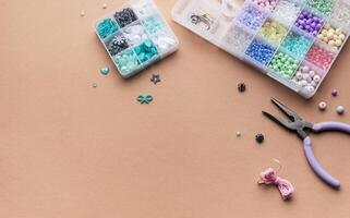 Crafting with colorful beads on a flat workspace with tools and containers in bright daylight photo