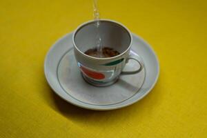 I pour boiling water into a mug with instant coffee. A mug in a saucer photo