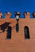 A massive, red-brick wall with small windows and a lantern photo
