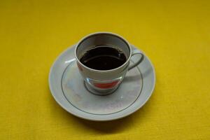 Instant coffee in a mug. A mug in a saucer on a yellow background. Top-down view photo