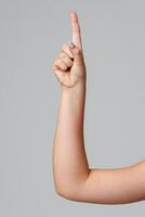 A raised hand with a pointed finger signaling attention in a neutral setting against a light background photo
