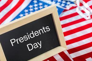 the text happy presidents day written in a chalkboard and a flag of the United States photo