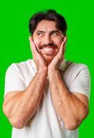 Young man with a beard smiles and poses in front of a bright green background photo