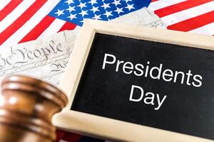 the text happy presidents day written in a chalkboard and a flag of the United States photo