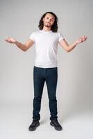 A man with curly hair expressing uncertainty while standing against a neutral background photo