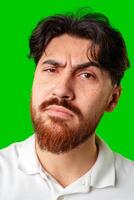 A young man with a beard showing a serious expression against a vibrant green background photo