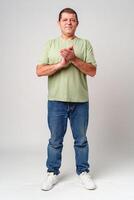 Elderly man claps his hands while standing against a neutral background in a casual light green shirt photo