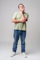 A thoughtful older man expresses gratitude while looking up with hope in a simple green shirt against a light backdrop photo