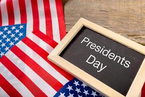 the text happy presidents day written in a chalkboard and a flag of the United States photo