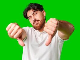 A man expresses disappointment with a thumbs down gesture against a bright green background photo