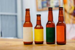 Four bottles of beer with different colored labels sit on a wooden table photo