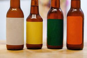 Four brown glass bottles with different colored labels sit on a wooden table photo