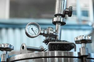 A pressure gauge on a stainless steel tank in an industrial setting displays the pressure reading photo