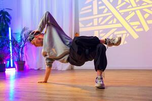A young man practices a breakdancing move in a studio with colorful lighting photo