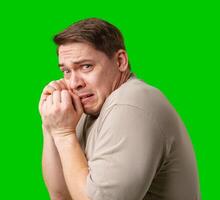 Man expressing fear while standing against a bright green background photo