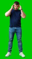 A man with closed eyes holds his head in a thoughtful pose against a bright green backdrop photo