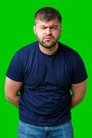 Man expressing confusion with crossed arms in front of a bright green background photo