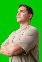 Confident man standing with crossed arms in front of bright green backdrop photo