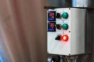A control panel with two digital displays shows the temperature and pressure in a factory photo