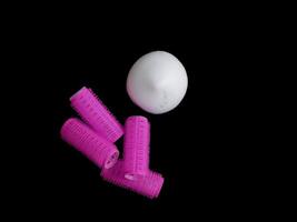 Products for hair styling - curlers and volume styling mousse isolated on black background with copy space photo