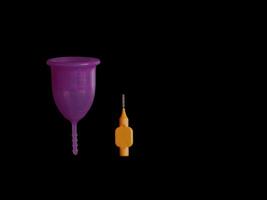 Menstrual cup with a special cleaning brush isolated on black background with copy space photo