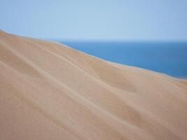 Sand textured pattern with copy space close up in Maspalomas, Gran Canaria. Abstract background wallpaper. Sand waves in a desert dune at the background of the sea photo